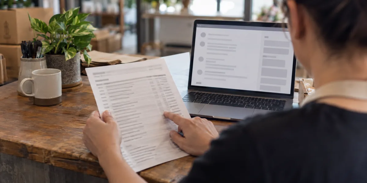 Business owner comparing a reviewer's name against a printed list of customer orders